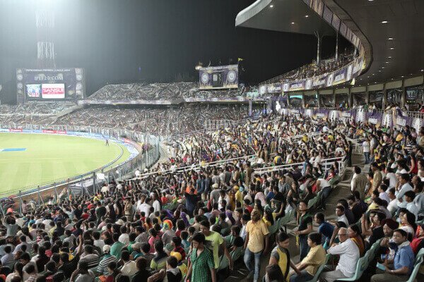 a packed stadium of fans watching a cricket game